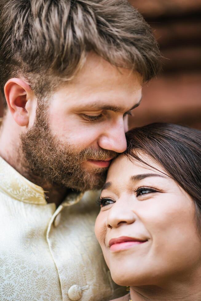 La novia asiática y el novio caucásico tienen tiempo romántico con el vestido de Tailandia foto