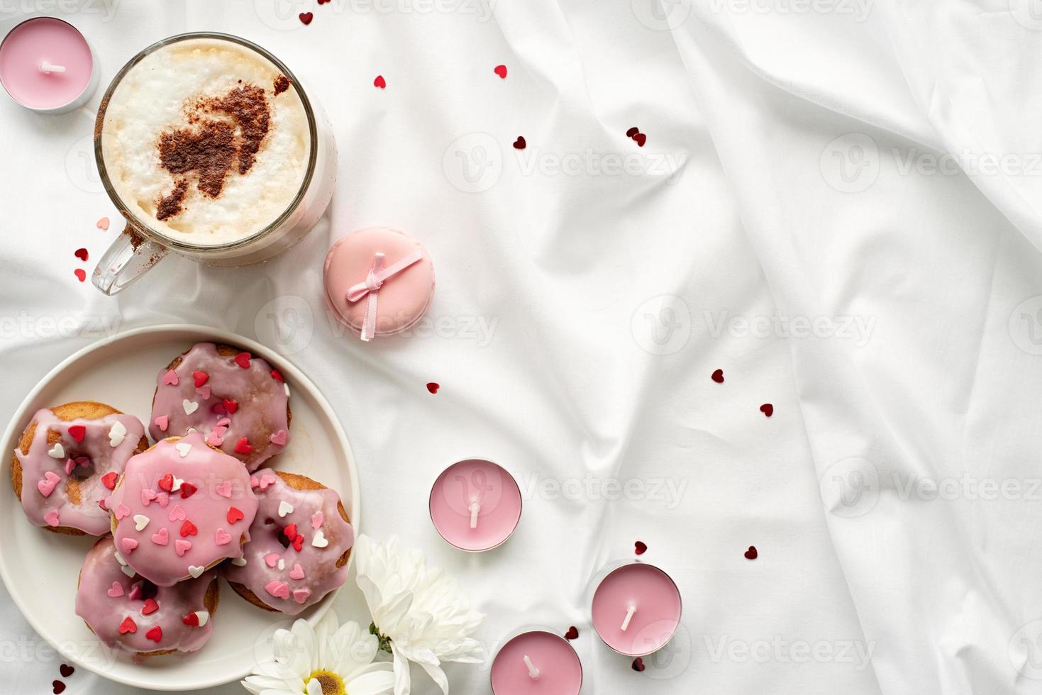 Donuts pequeños en la cama blanca con una taza de café foto