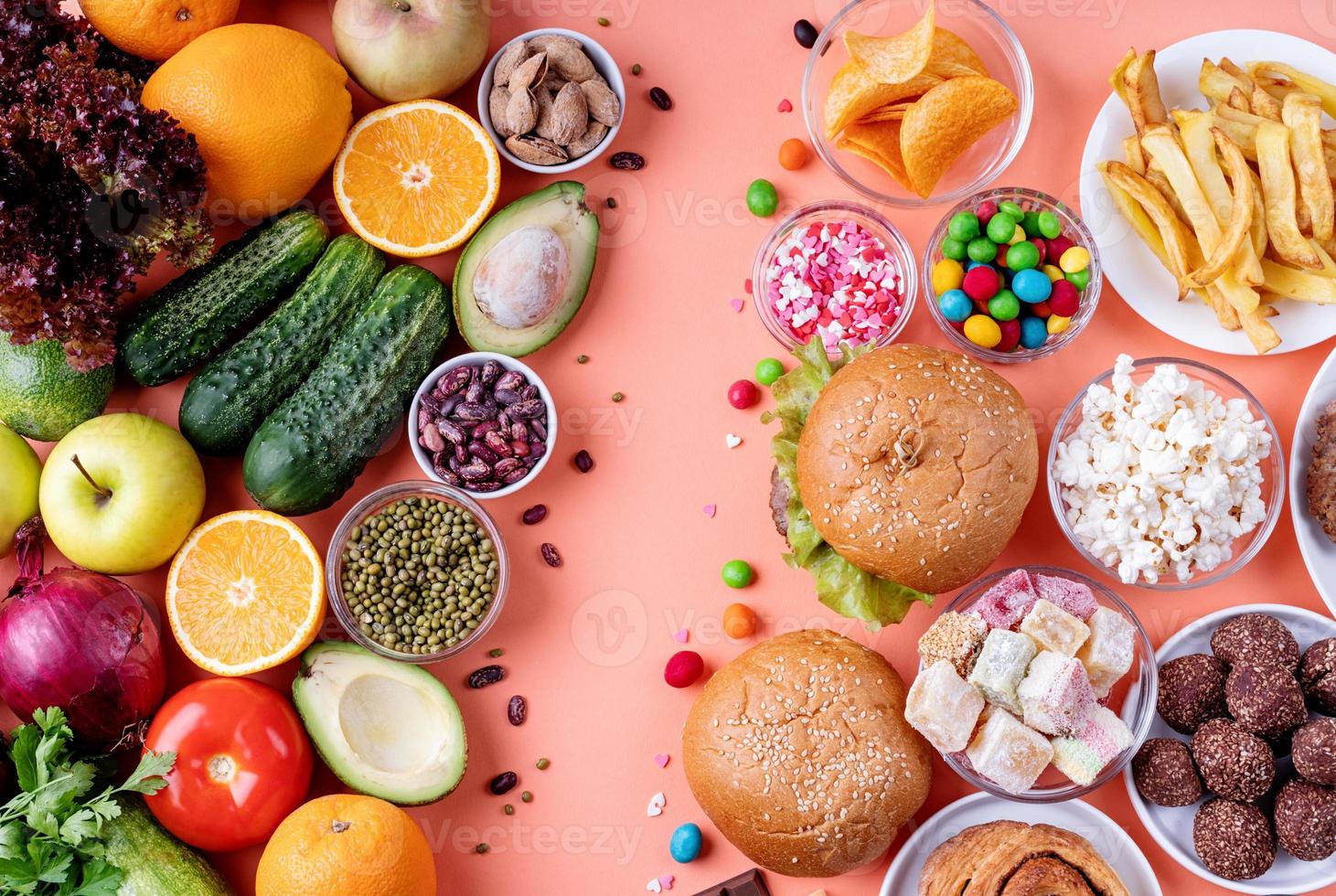 Frutas y verduras vs dulces y comida rápida vista superior plana sobre fondo naranja foto