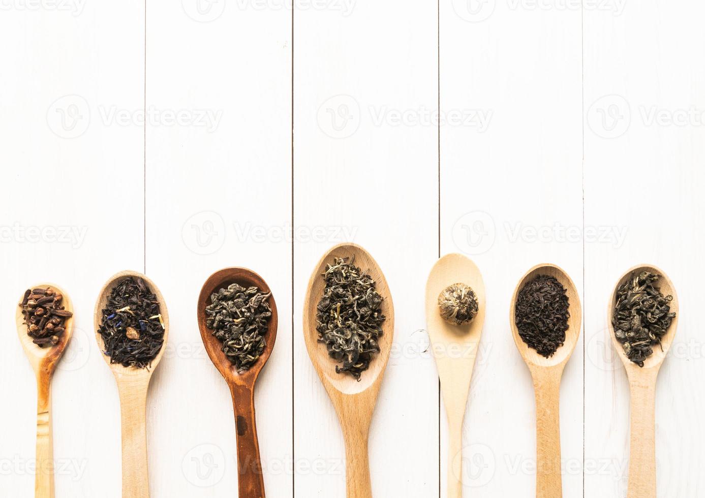 assortment of dry tea in spoons, isolated on white photo