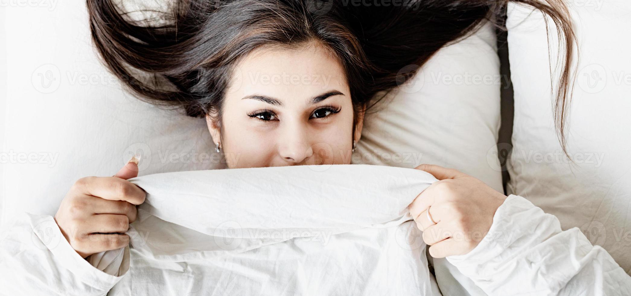 joven y bella mujer morena durmiendo en la cama foto