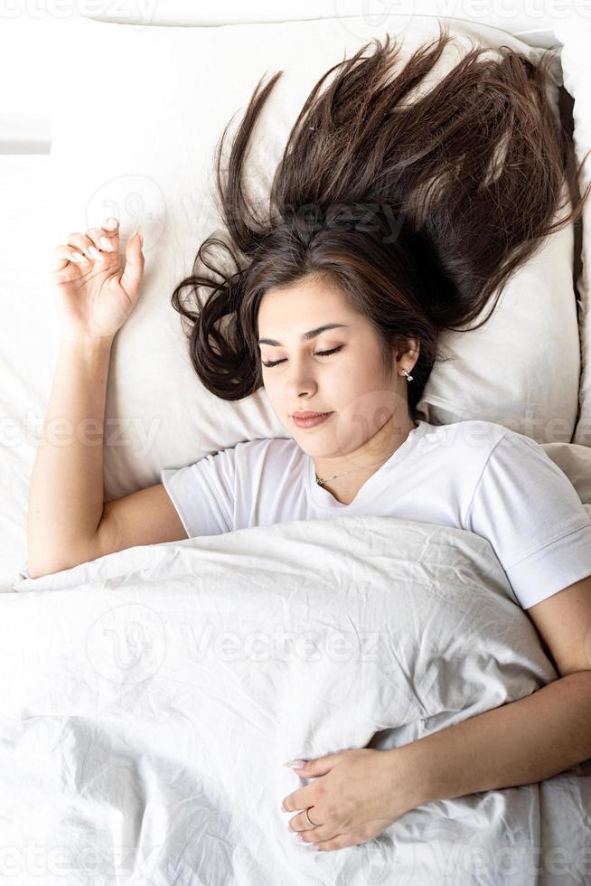 joven y bella mujer morena durmiendo en la cama foto