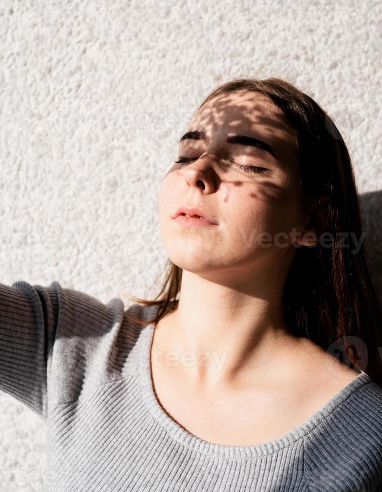 Retrato de una bella mujer joven con un patrón de sombra en la cara y el cuerpo en forma de flores. foto