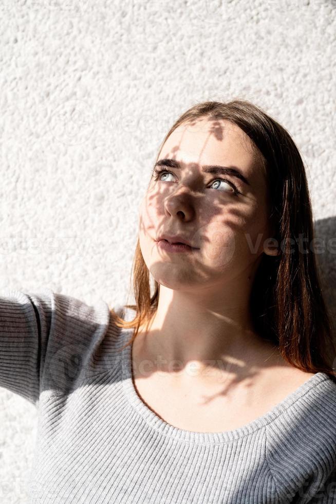 Portrait of a beautiful young woman with a shadow pattern on the face and body in the form of flowers photo