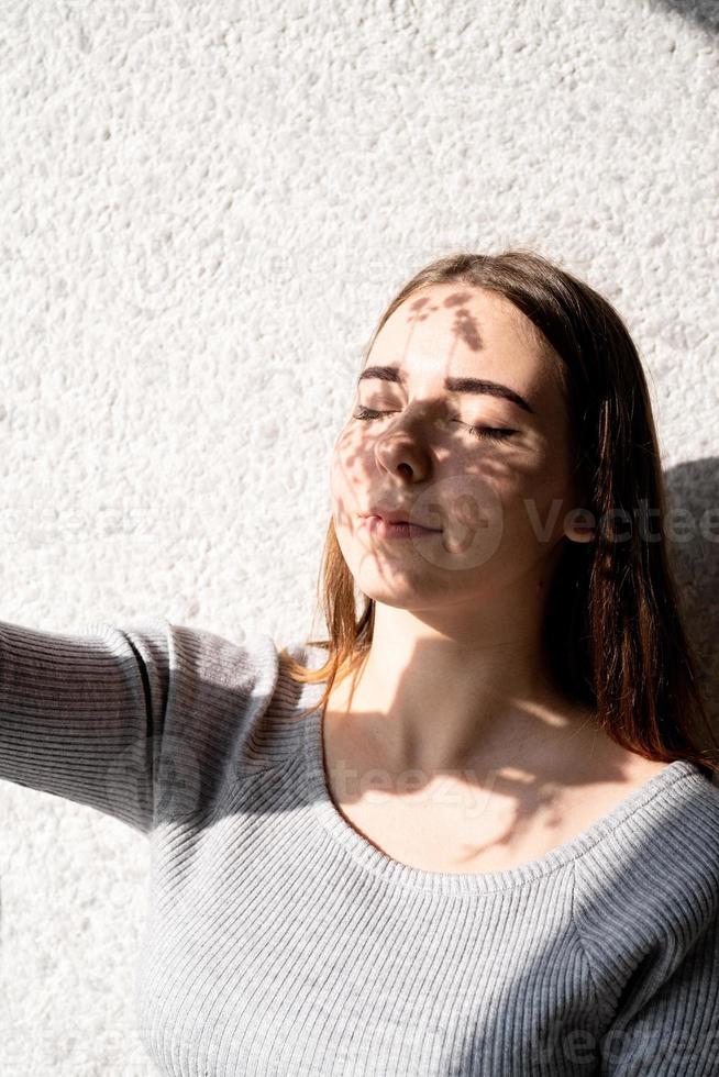 Retrato de una bella mujer joven con un patrón de sombra en la cara y el cuerpo en forma de flores. foto