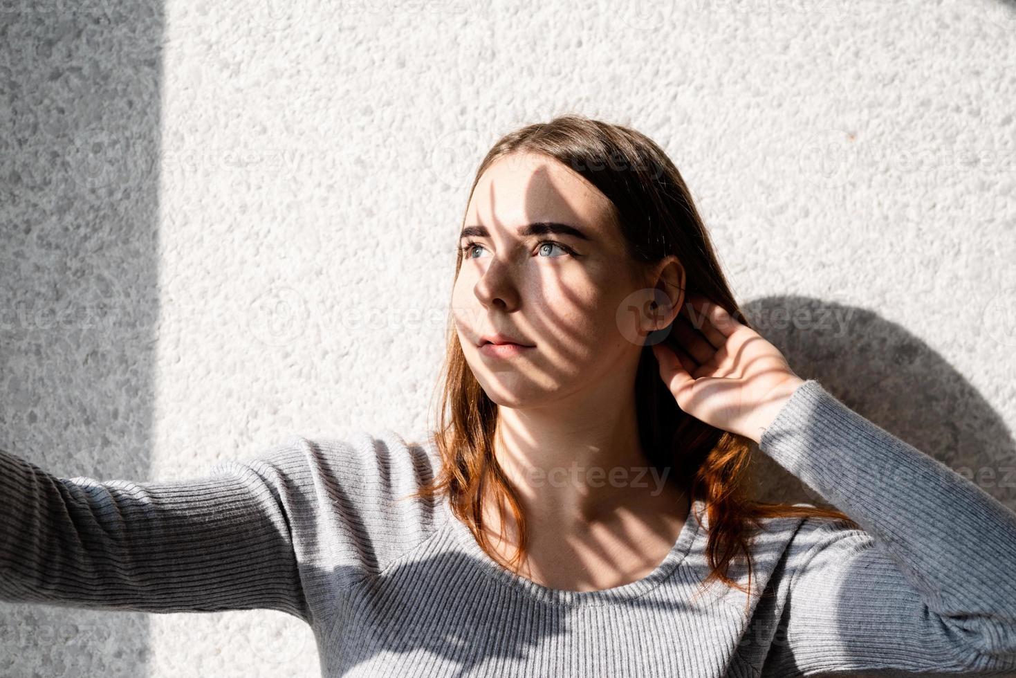 Portrait of a beautiful young woman with a shadow pattern on the face and body in the form of palm leaf photo