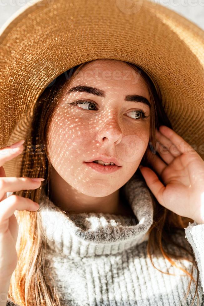 Retrato de una bella mujer joven con un sombrero de paja con un patrón de sombra en la cara y el cuerpo foto