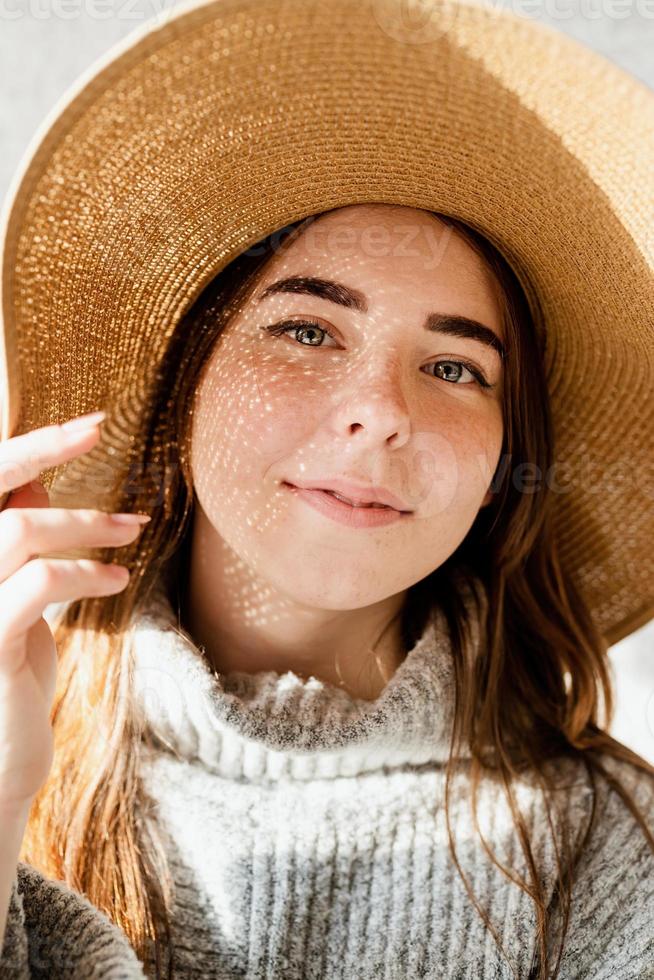 Retrato de una bella mujer joven con un sombrero de paja con un patrón de sombra en la cara y el cuerpo foto