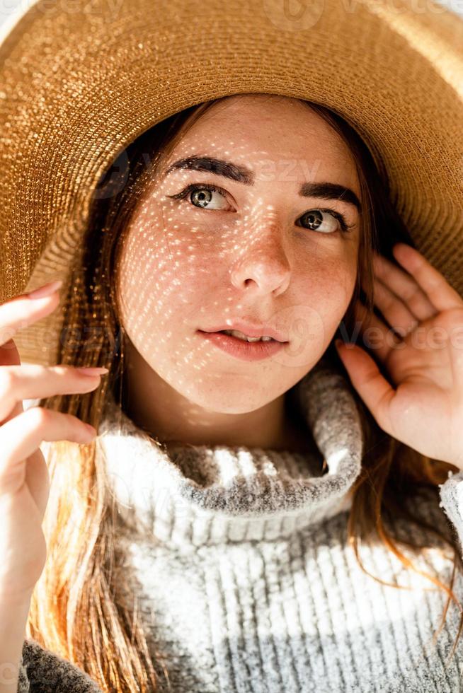 Retrato de una bella mujer joven con un sombrero de paja con un patrón de sombra en la cara y el cuerpo foto