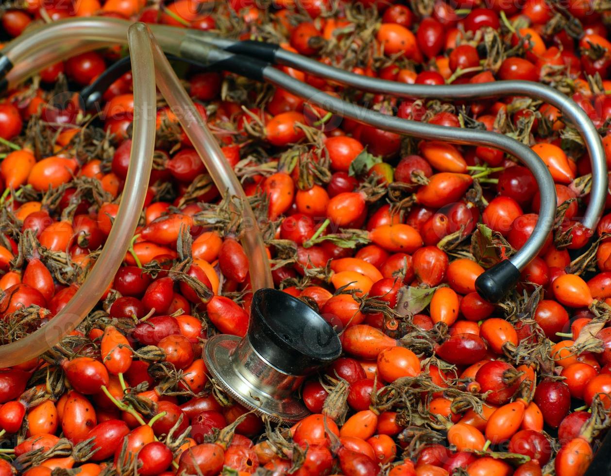 The stethoscope lies on the rose hips. Concept - blood pressure treatment photo