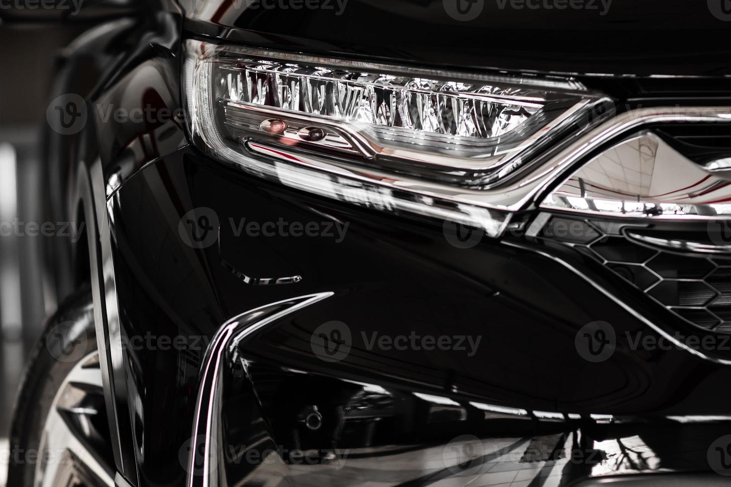 Modern luxury car close-up. Concept of expensive, sports auto. Headlight lamp of new cars,copy space. A modern and elegant car illuminated. photo
