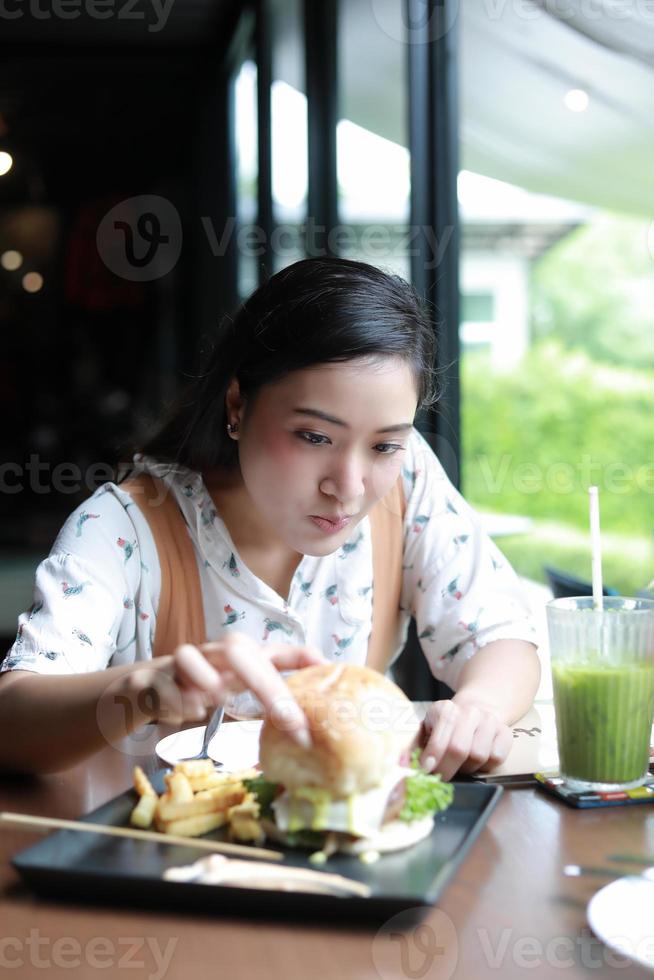 Mujeres asiáticas sonrientes y felices y disfrutaron comiendo hamburguesas en el café y el restaurante en el momento de relajarse foto