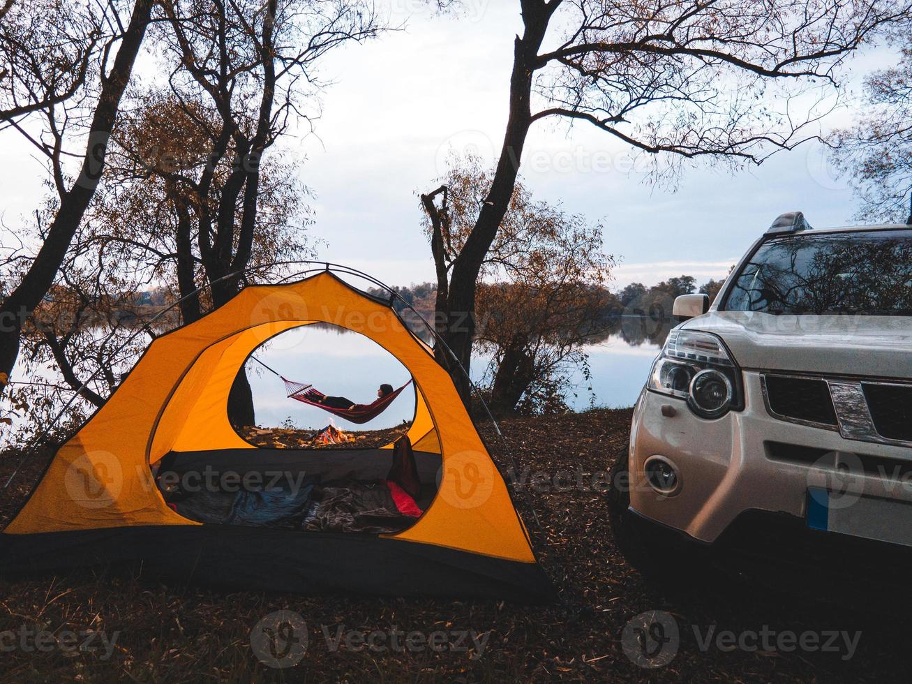 mujer acostada en la hamaca en la orilla del lago. concepto de campamento de otoño foto