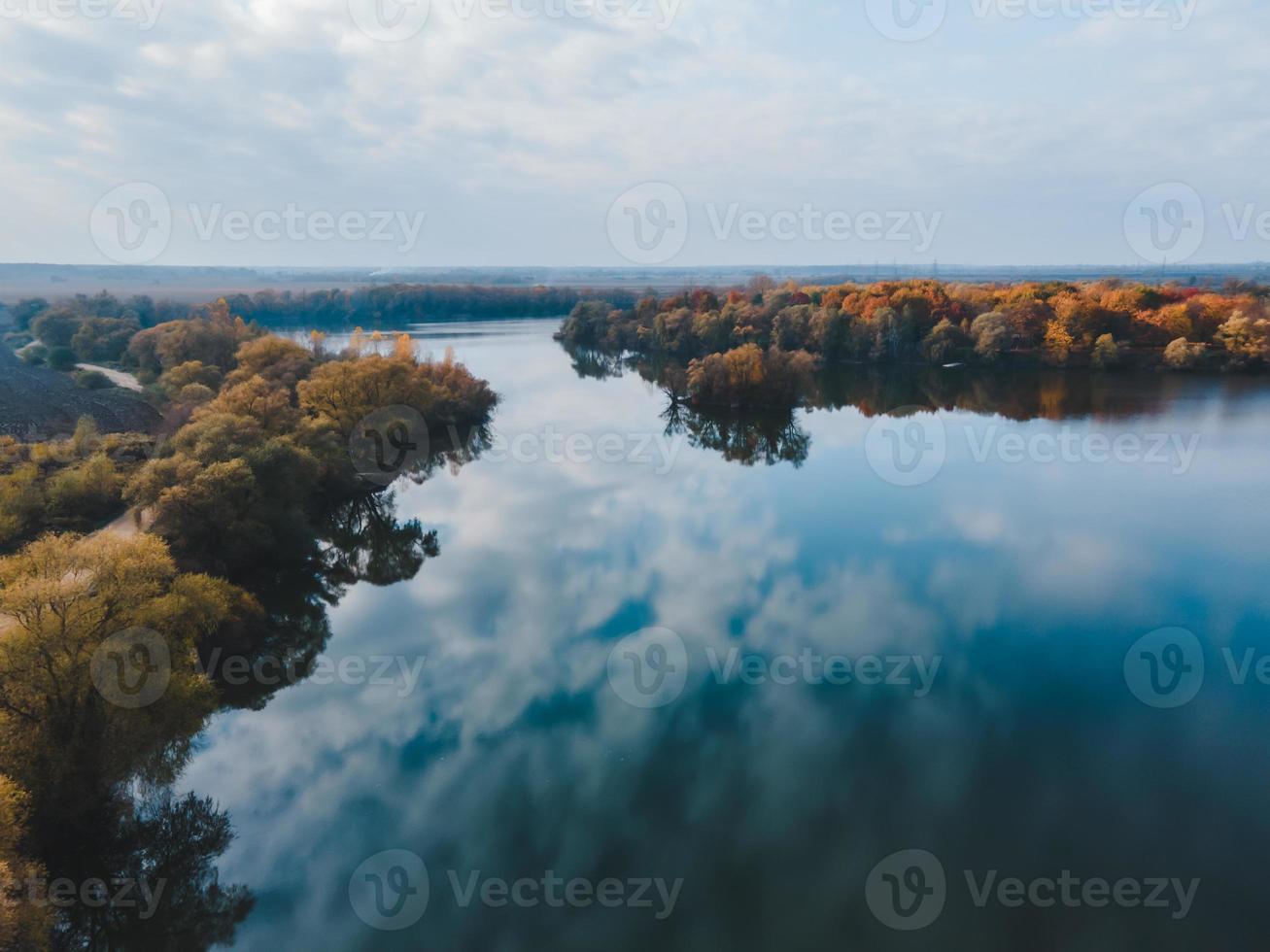 Aerial view of autumn forest with lake sky reflected in water photo