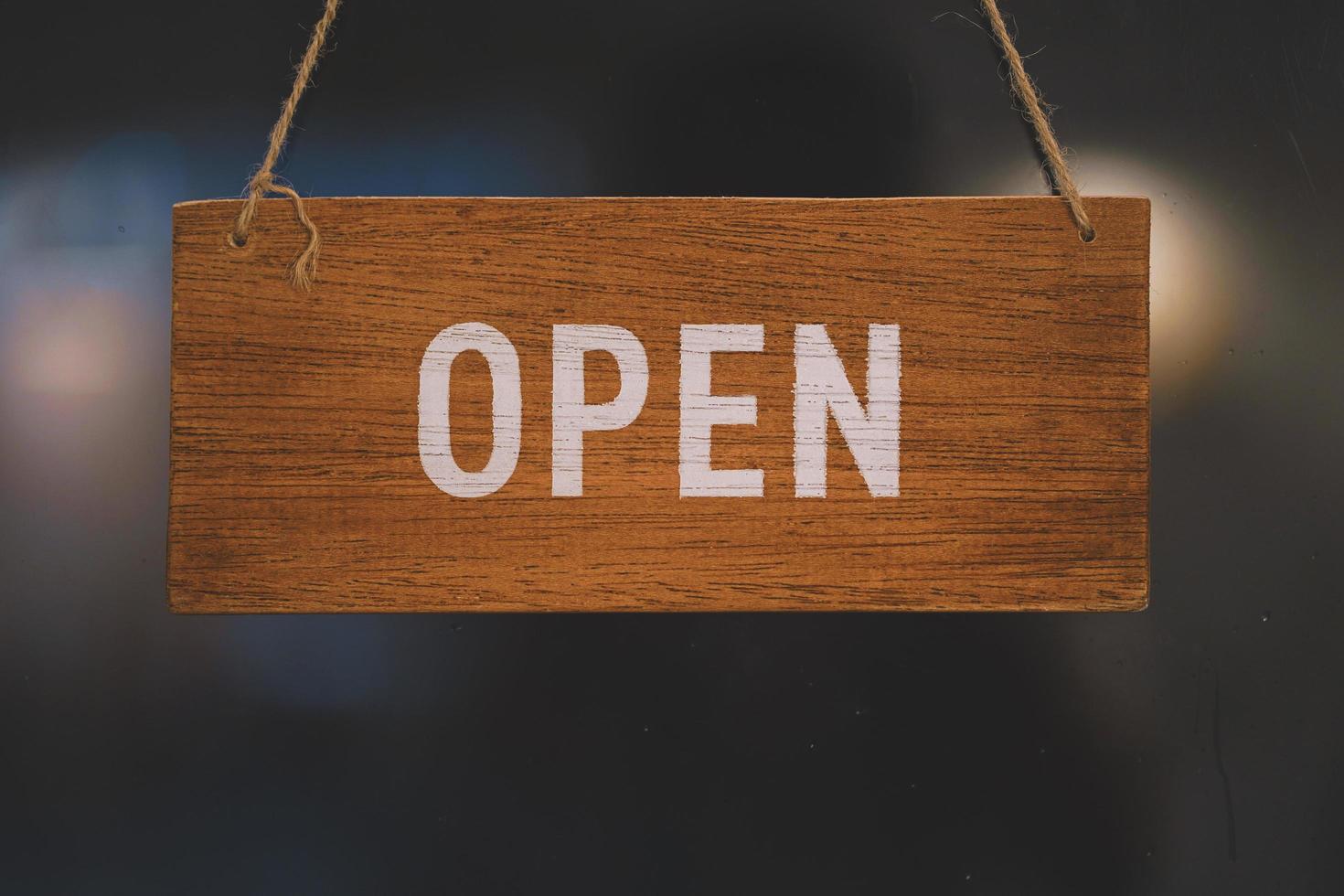 Open wooden sign broad through the glass of door in cafe. Business service and food concept photo