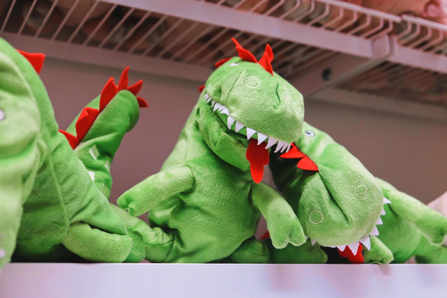 Green plush dinosaur doll on shelf photo