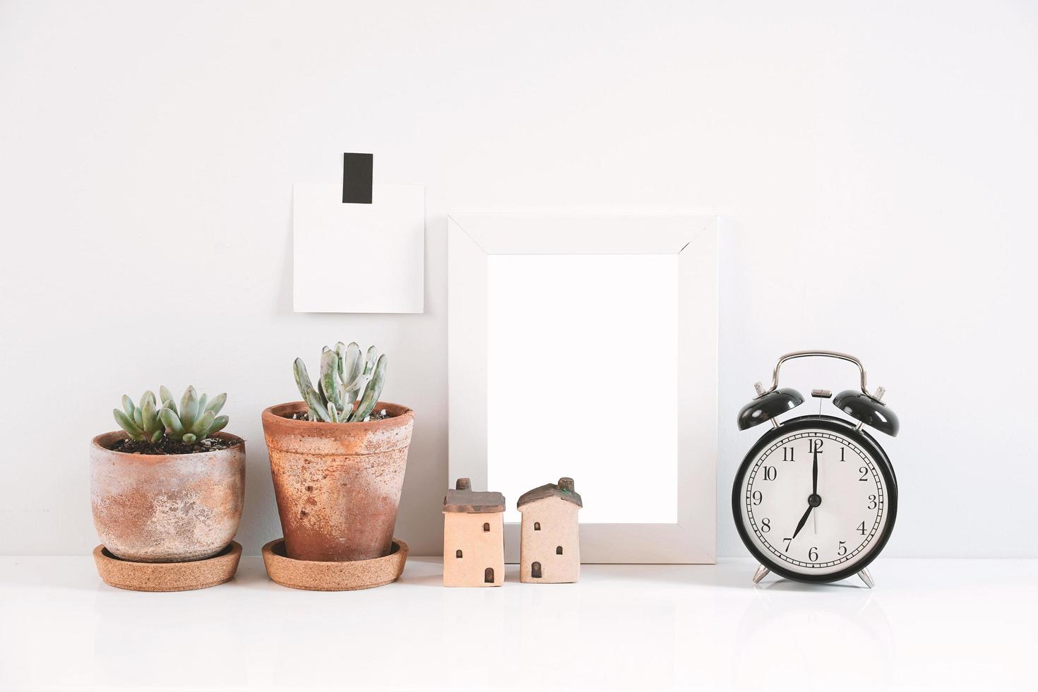 Succulents or cactus in clay pots over white background on the table with the clock and picture frame photo