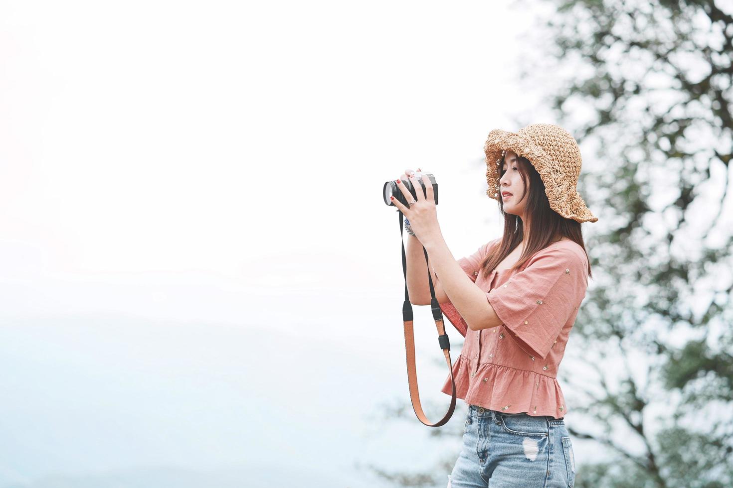 Young beautiful Asian traveler woman using digital compact camera and smile, looking at copy space. Journey trip lifestyle, world travel explorer or Asia summer tourism concept photo