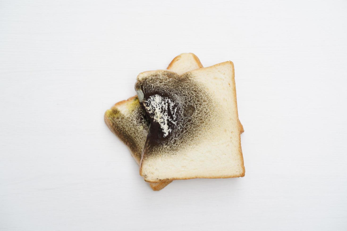 Moldy bread on wooden white background photo