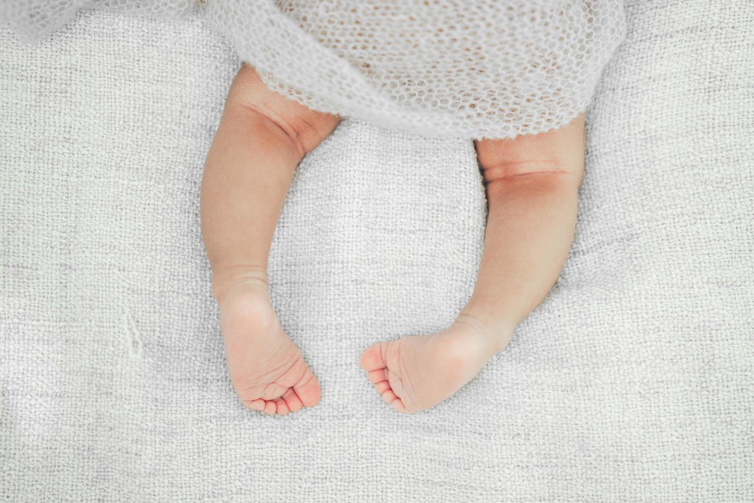 piernas de bebé recién nacido en la cama. lindo bebé acostado en la cama foto