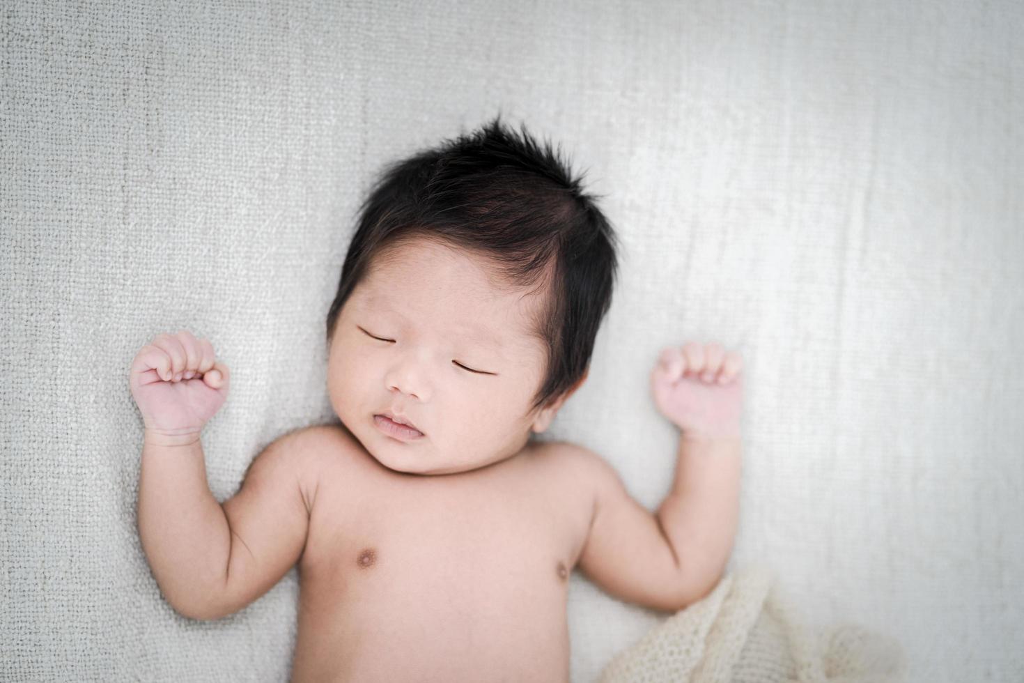 Adorable bebé recién nacido durmiendo pacíficamente sobre una manta blanca, vista superior foto