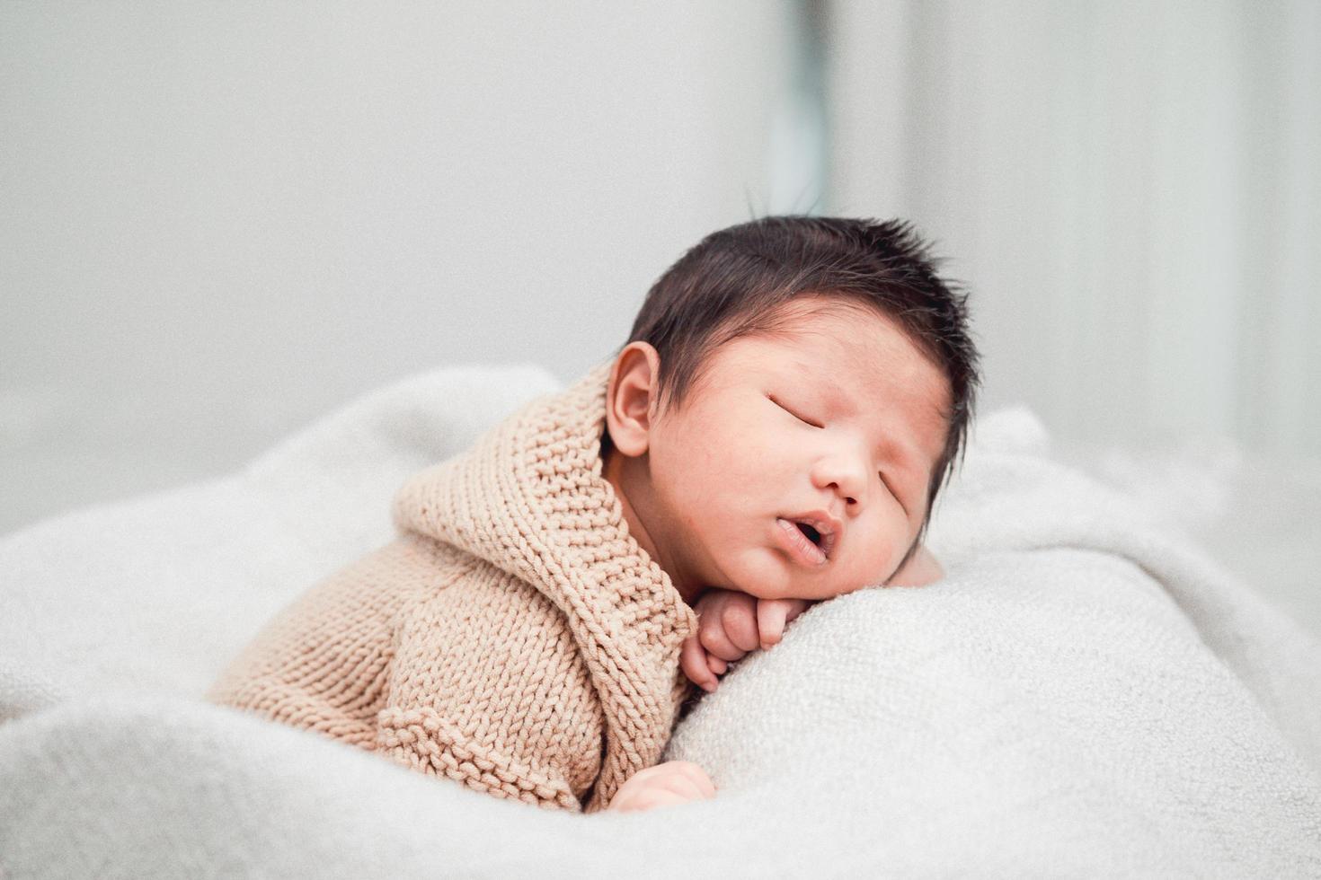 Adorable newborn baby peacefully sleeping on a white blanket photo