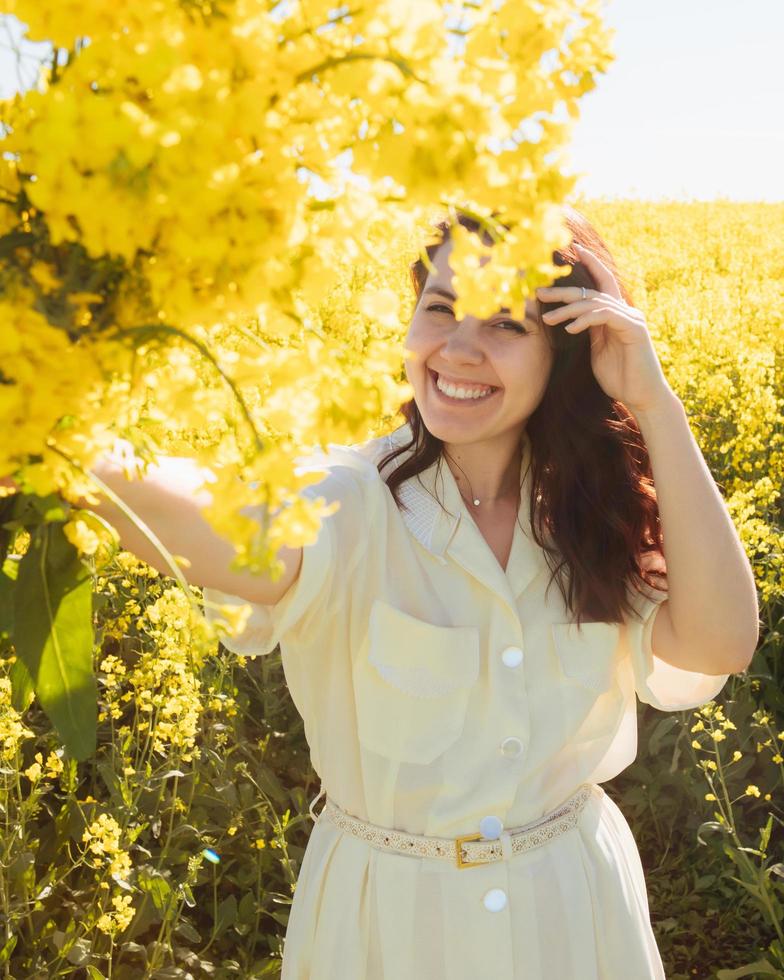 mujer de pie en el campo de colza foto