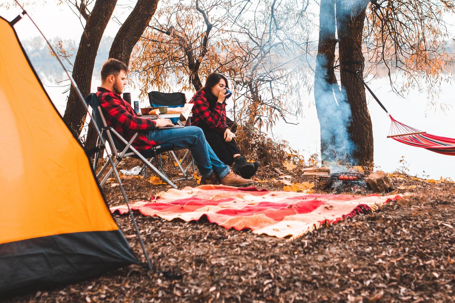 Smiling happy couple resting near fire cooking food photo