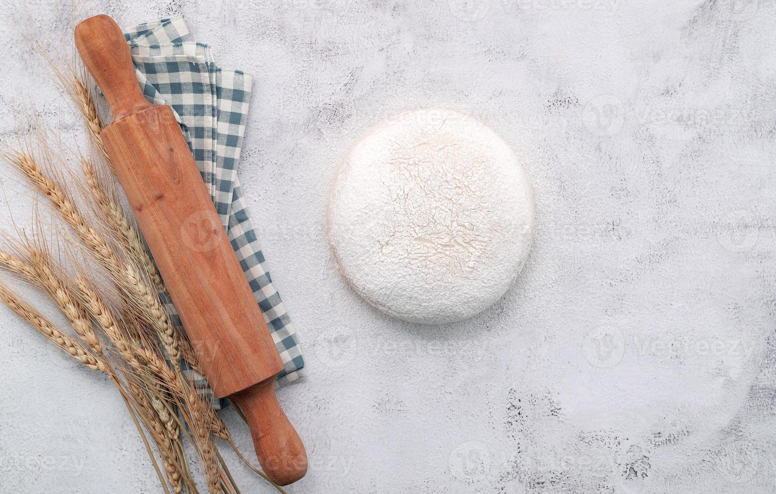 Wheat ears and wheat grains setup with rolling pin on white concrete background. photo