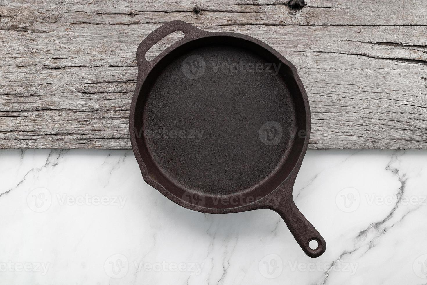 Empty old cast iron skillet set up on white marble  background with flat lay and copy space. photo