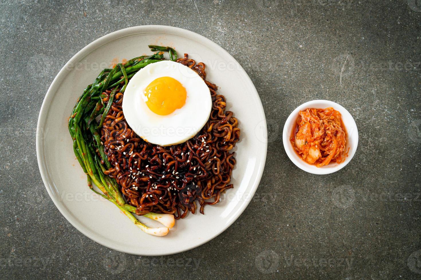 fideos instantáneos secos coreanos con salsa negra picante con huevo frito y kimchi foto