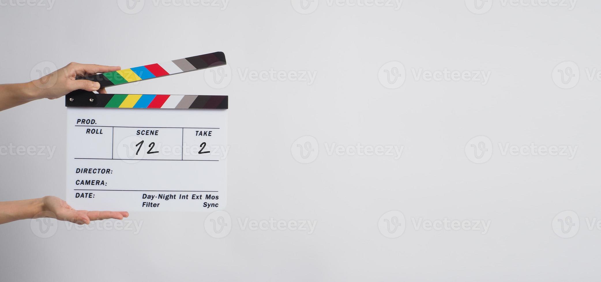 A hand is holding clapper board or movie slate use in video production and movie, film, cinema industry on black background. It has written in number. photo