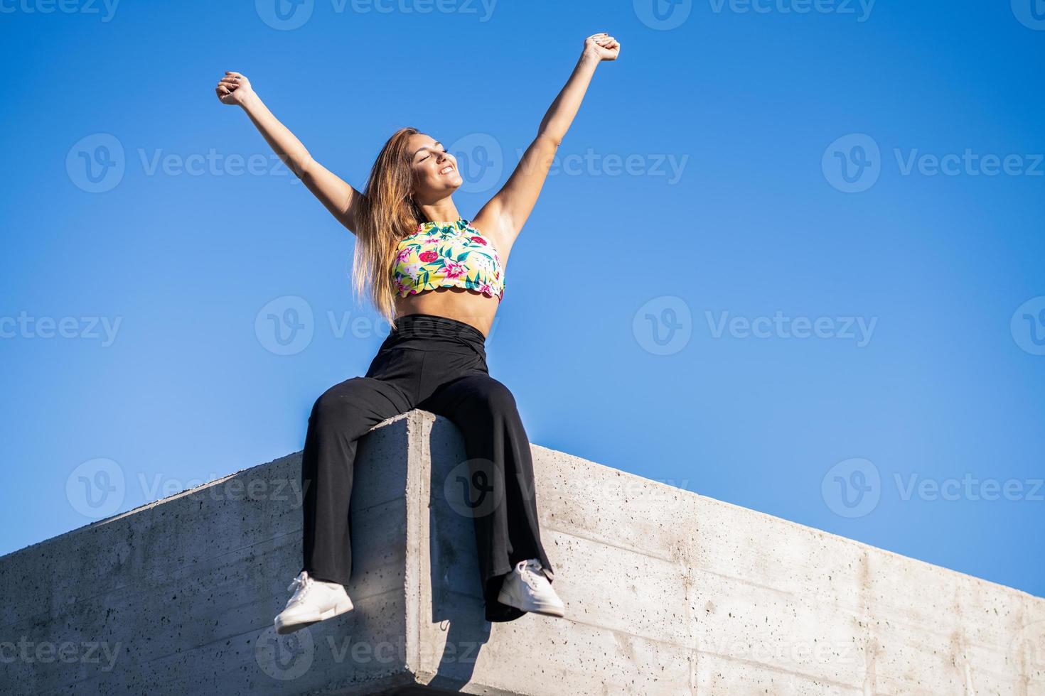 Mujer joven abriendo los brazos contra el cielo azul foto