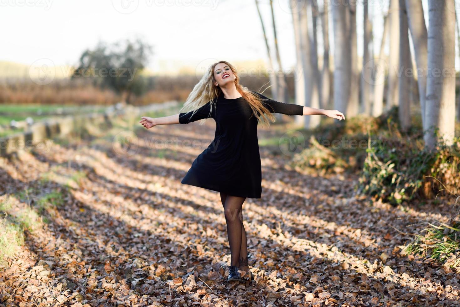 Joven mujer rubia bailando en el bosque de álamos foto