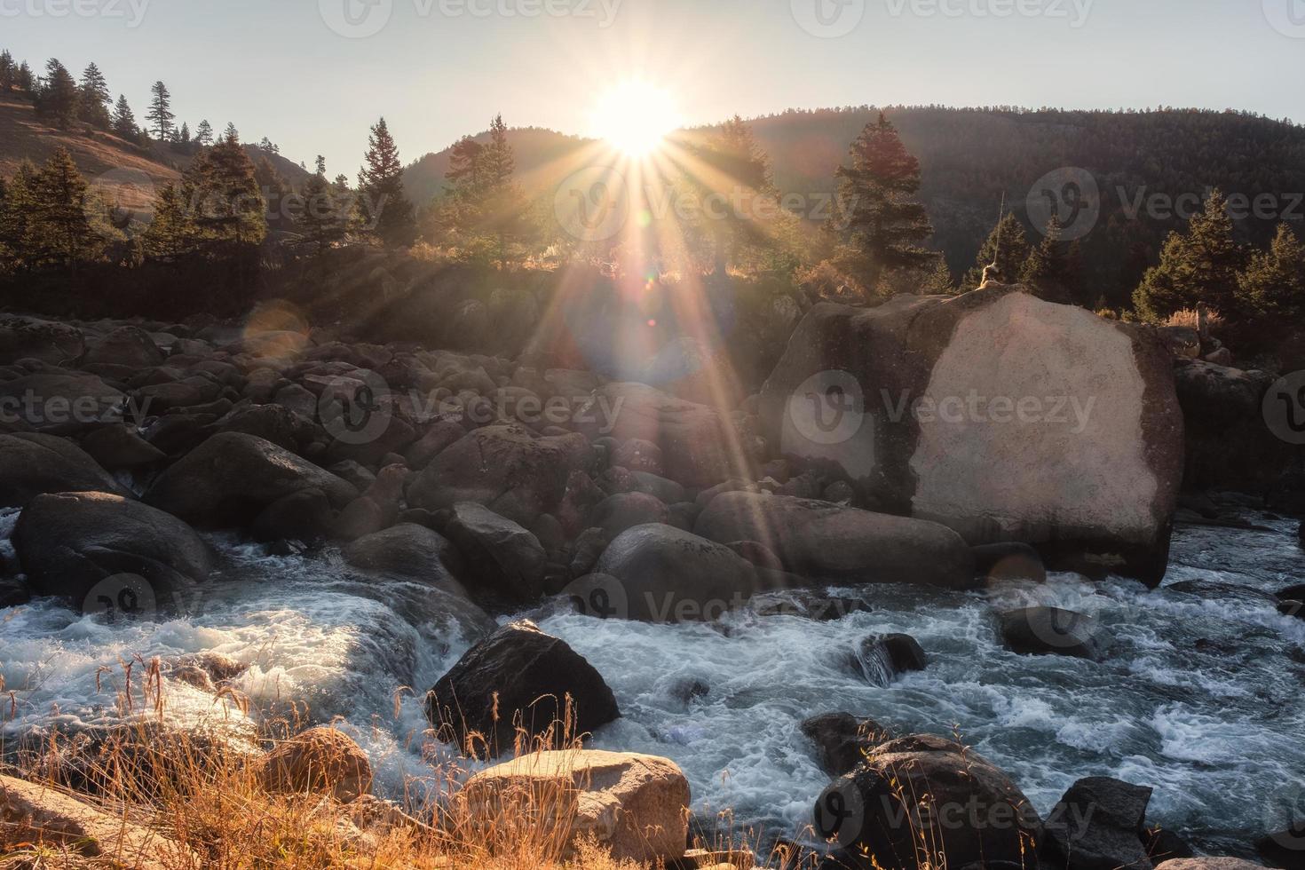 Puesta de sol brillando en el bosque de pinos con cascada que fluye en el parque nacional foto