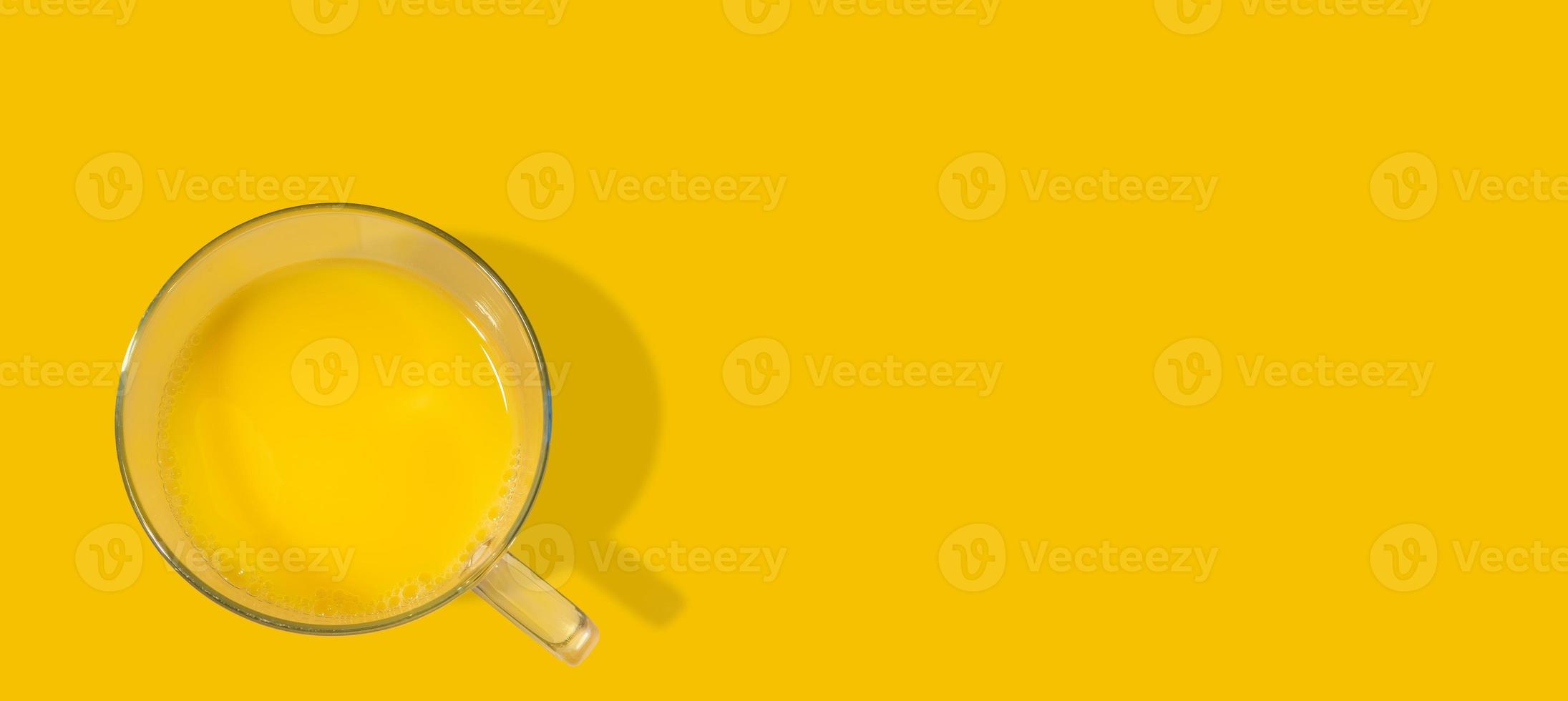 Banner with a glass filled with orange juice just made from fresh fruits, at solid orange background with copy space. Concept of healthy food, vitamins and healthy life. photo