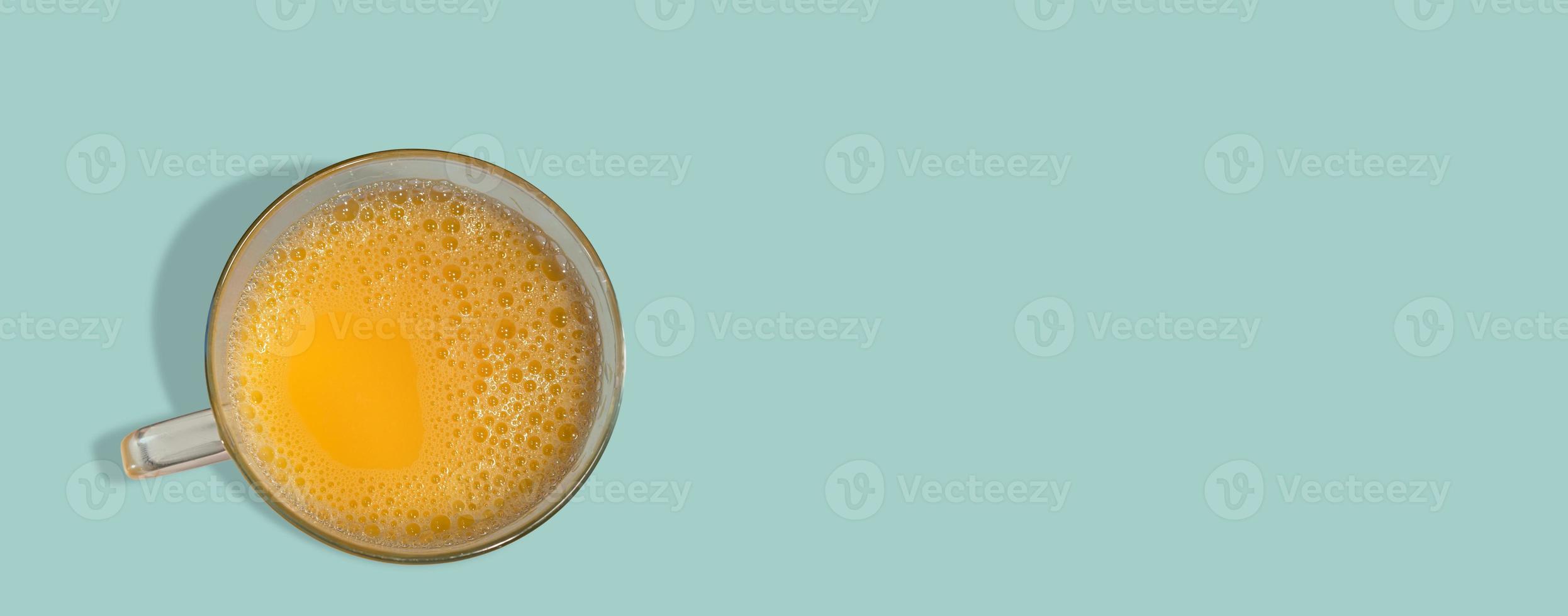 Banner with a glass filled with orange juice just made from fresh fruits, at solid turquoise background with copy space. Concept of healthy food, vitamins and healthy life. photo