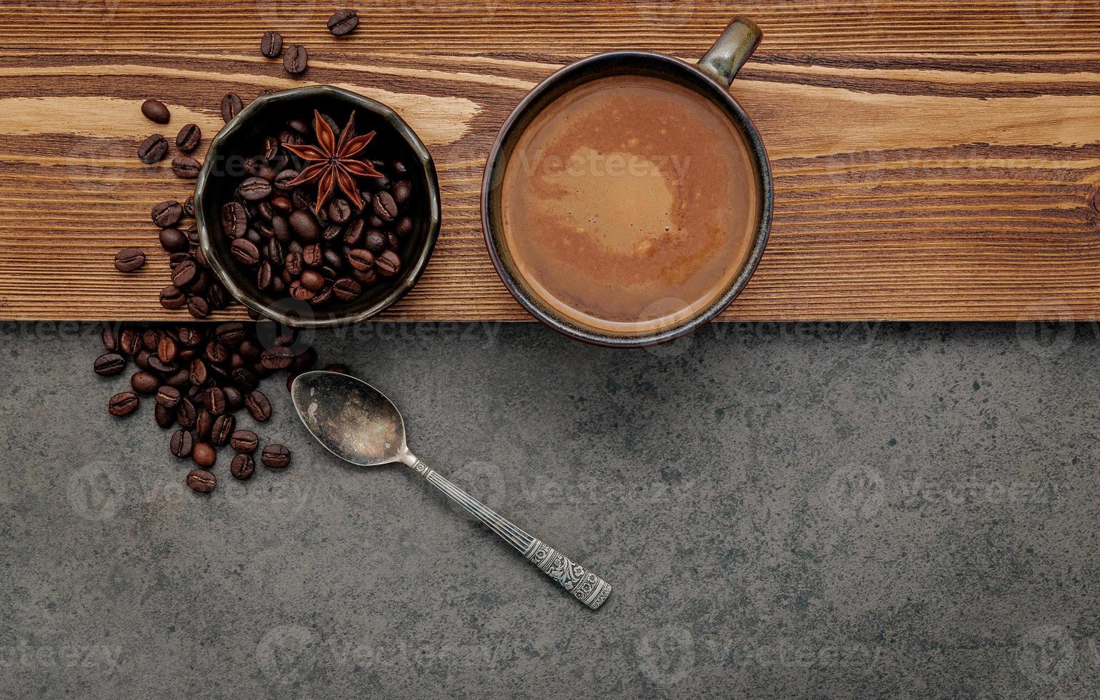 Roasted coffee beans with coffee cup setup on dark stone background. photo