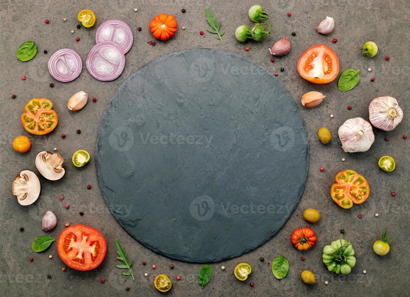 The ingredients for homemade pizza set up on dark stone background. photo