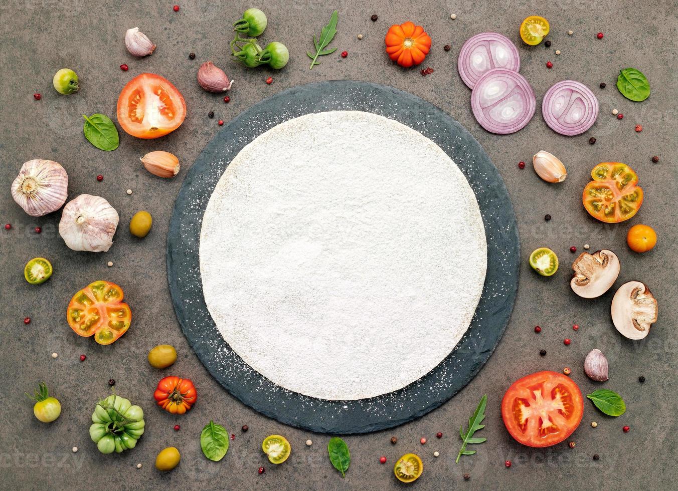 The ingredients for homemade pizza set up on dark stone background. photo