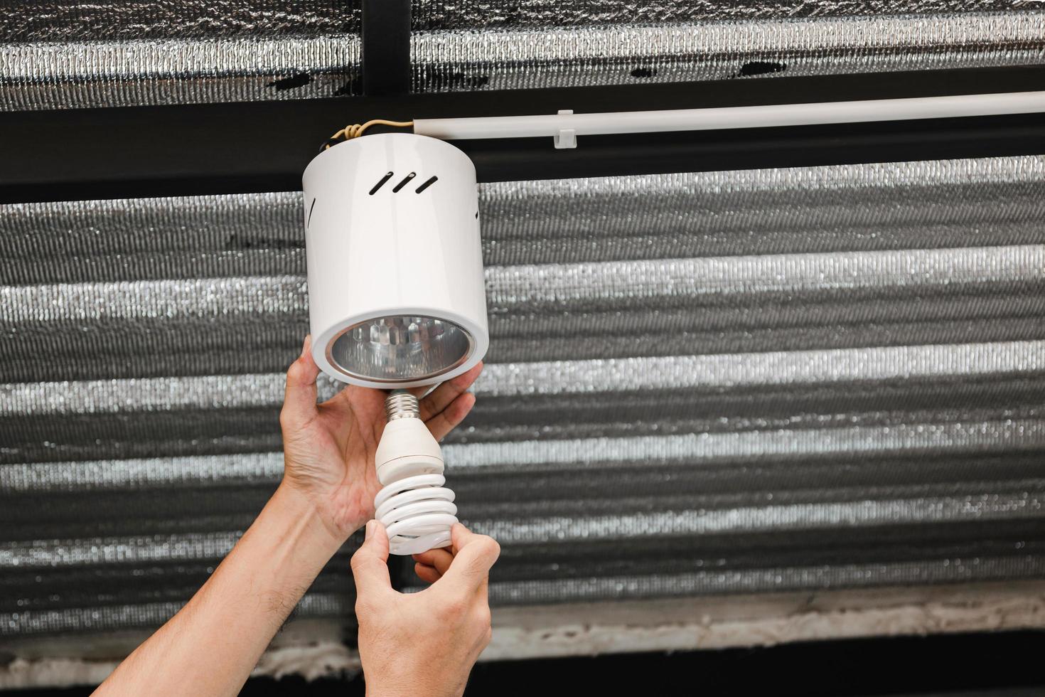 Human hand is removing a fluorescent light bulb in a circular ceiling lamp to turn it into an LED bulb. photo