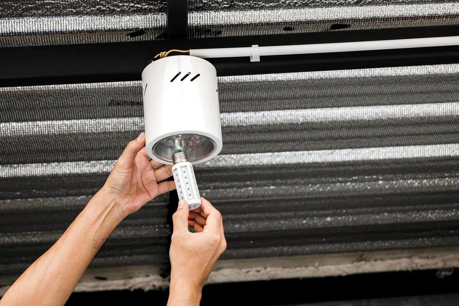 Human hand is installing an LED light bulb in a circular ceiling lamp. photo