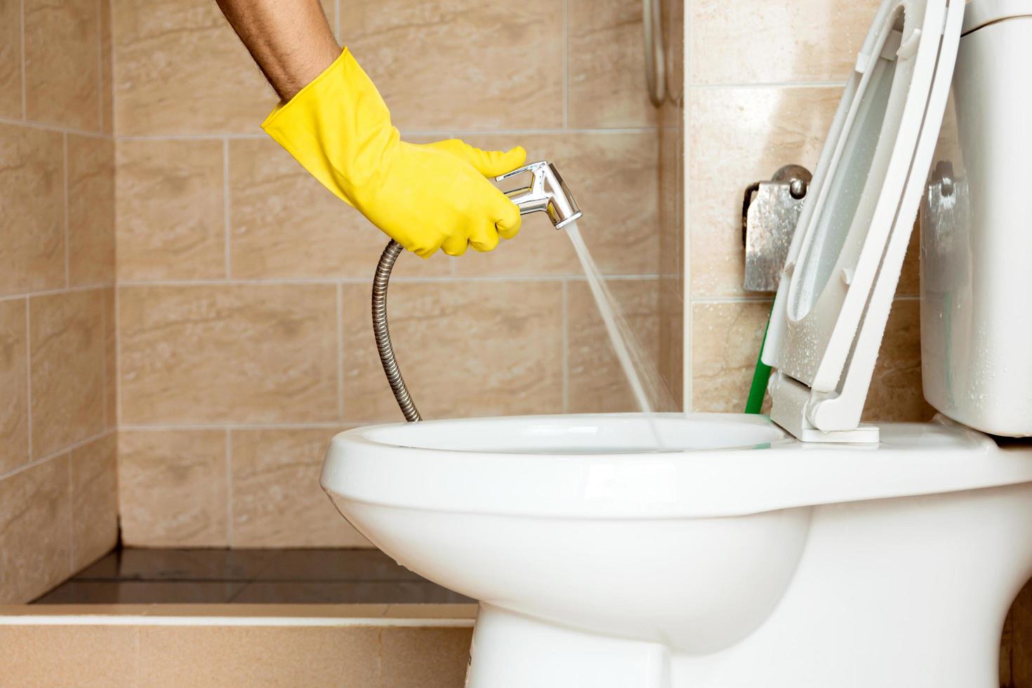 Using a hose to spray water to clean the toilet bowl. 3557198 Stock