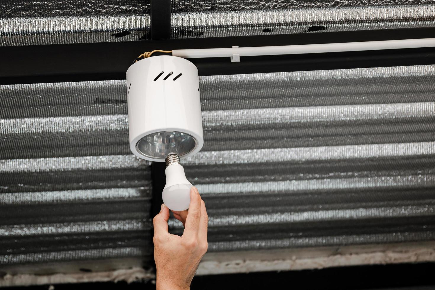 Human hand is installing an LED light bulb in a circular ceiling lamp. photo