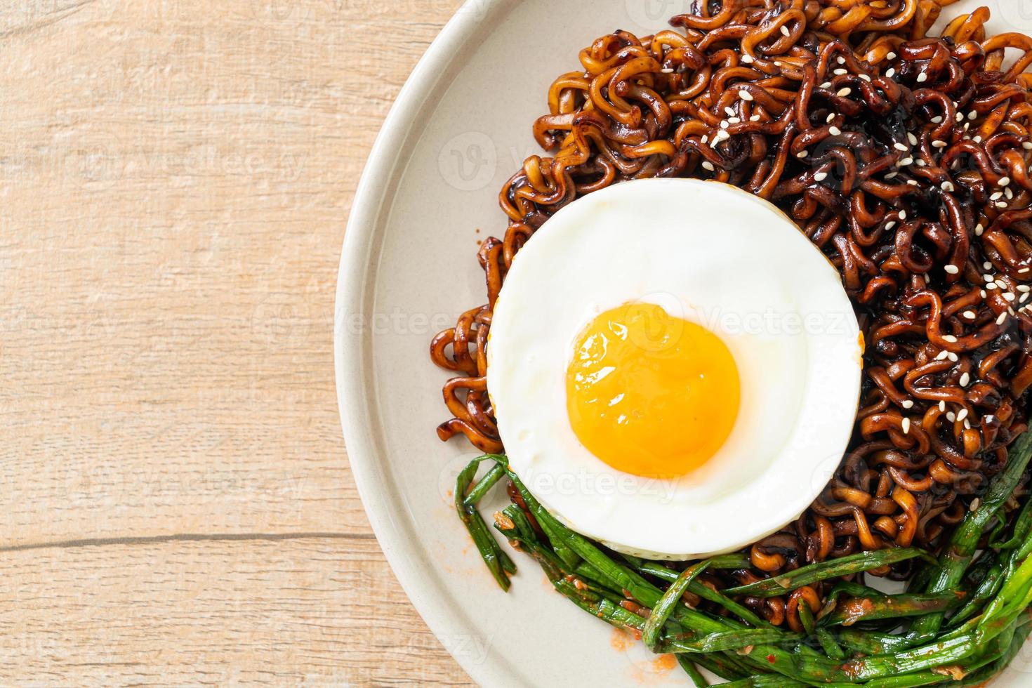 dried Korean spicy black sauce instant noodles with fried egg and kimchi photo