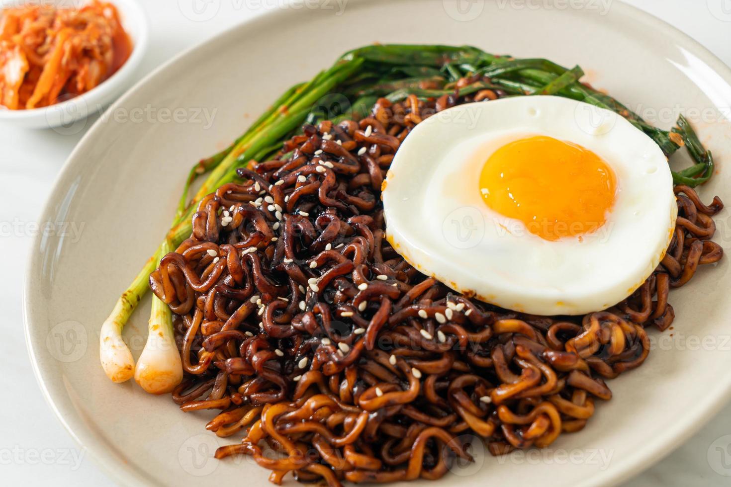 dried Korean spicy black sauce instant noodles with fried egg and kimchi photo