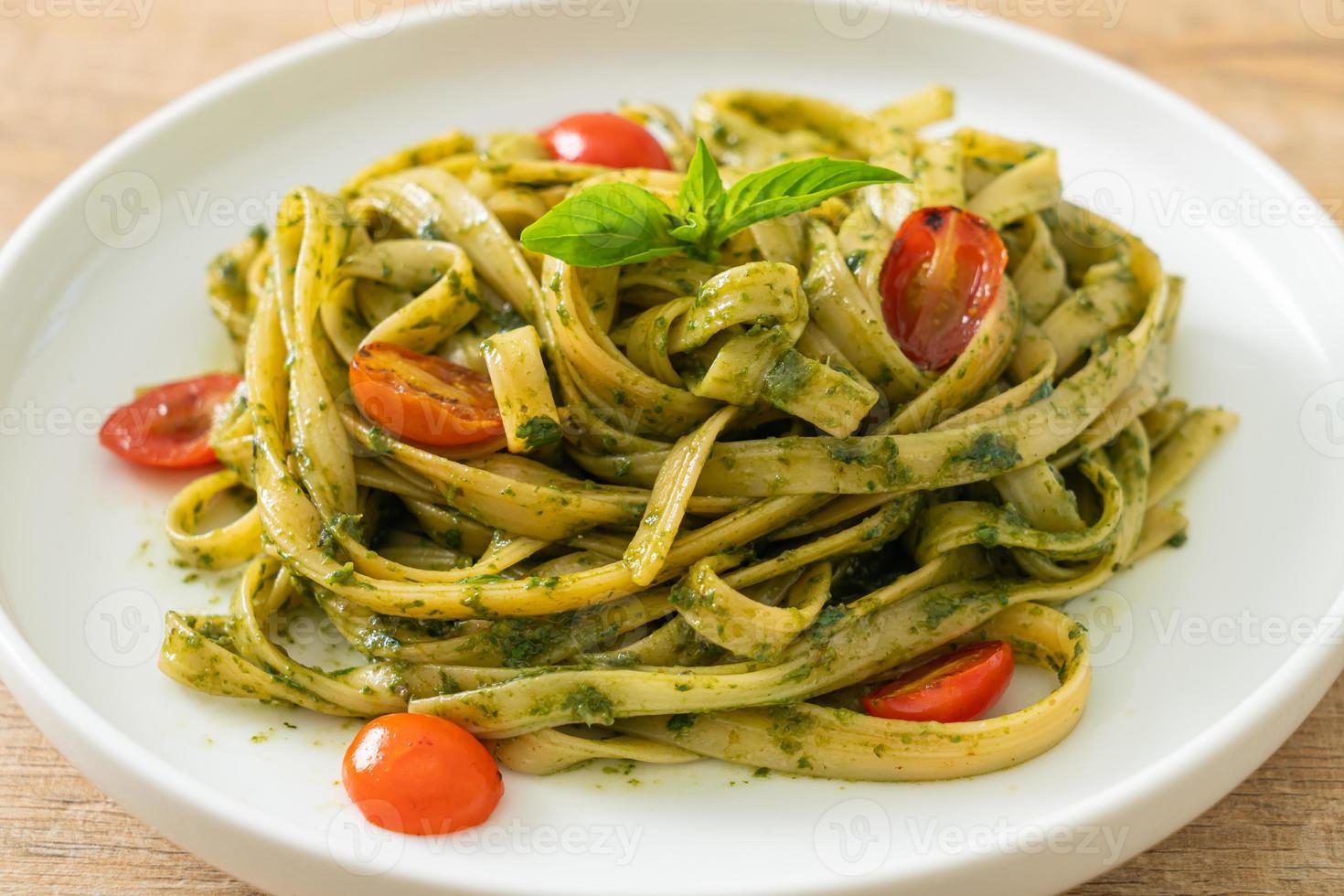 espaguetis fettuccine con salsa pesto y tomates foto