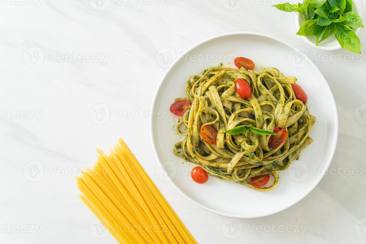 espaguetis fettuccine con salsa pesto y tomates foto