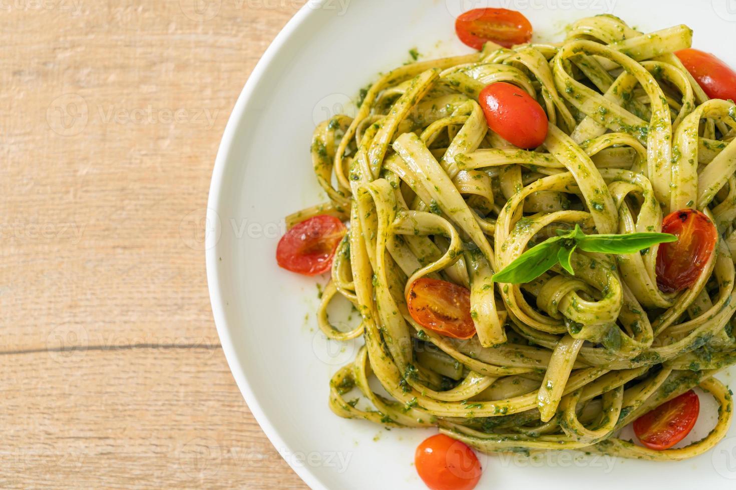 espaguetis fettuccine con salsa pesto y tomates foto