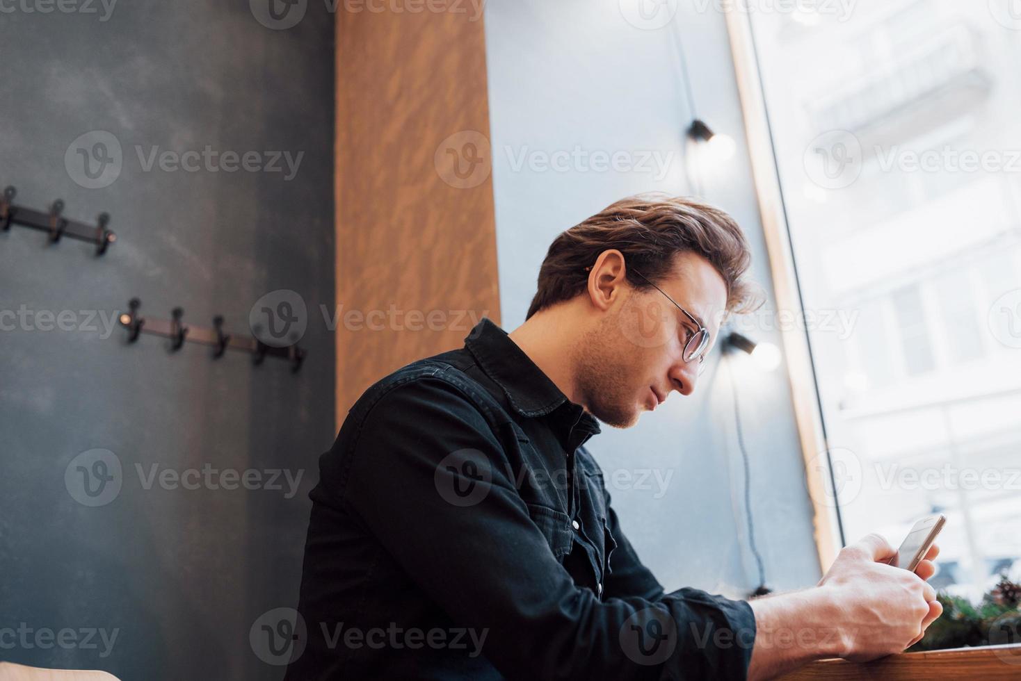 enfoque suave.hombre sosteniendo y usando el teléfono de venta.Mientras se sienta y se relaja en el sofá en la casa moderna.concepto para jóvenes que trabajan con dispositivos móviles foto